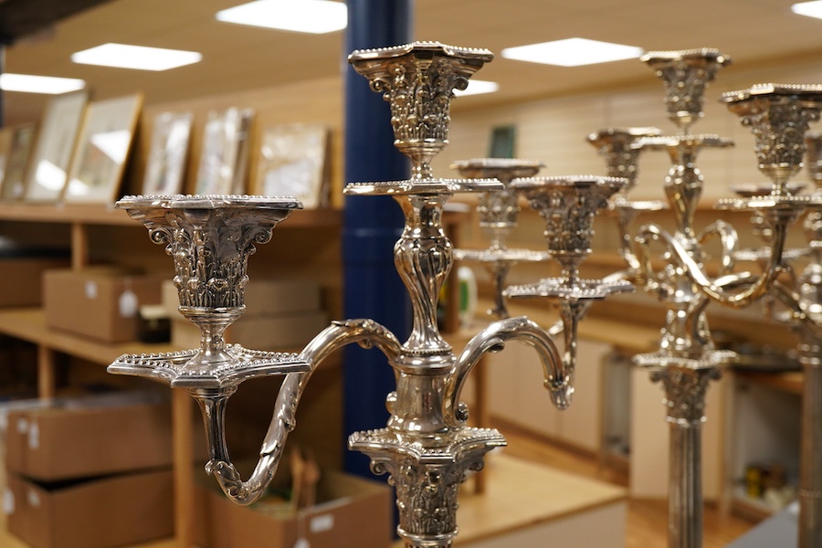 A garniture of 19th century silver plated Corinthian column candelabra, comprising a pair of two branch, three light candelabra and matching four branch, five light candelabrum, with detachable acanthus leaf capped scrol